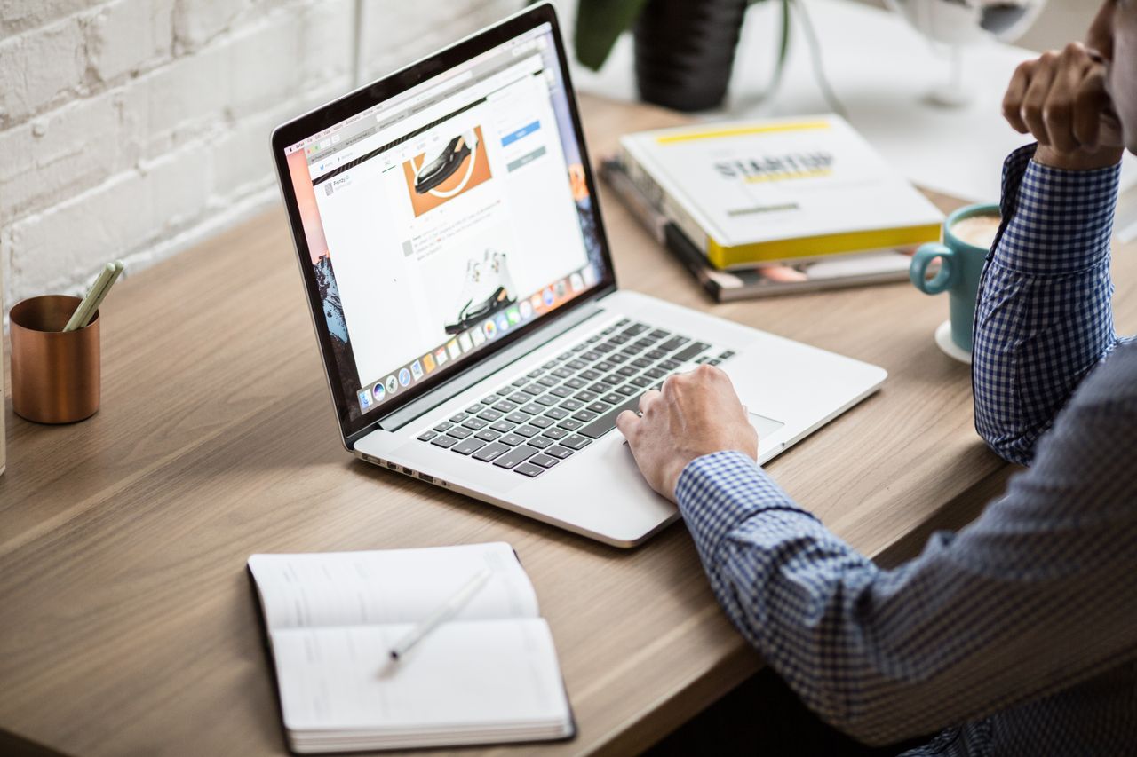 An adult using a laptop in a contemporary office environment, conveying focus and productivity.